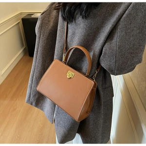 Brown vintage leather handbag with gold geometric clasp shown on a model