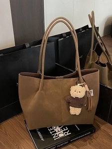 Grand sac cabas marron en daim avec pendentif ours en peluche sur des livres