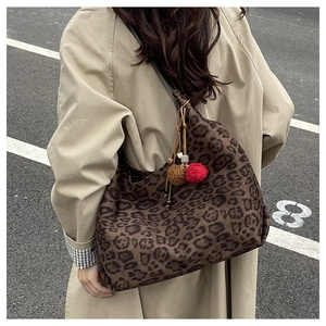 Detail of a large leopard print tote bag with plush charms shown on a trench coat
