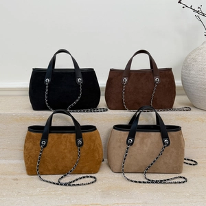 Detailed arrangement of four suede tote bags in earthy tones on a marble display