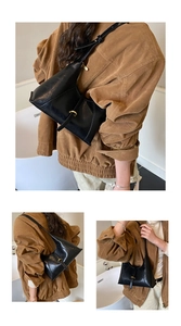 Detailed view of black soft leather shoulder bag with metallic buckle and curved top design