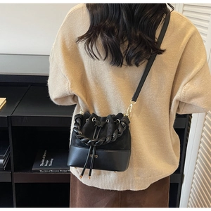 Detail of black patchwork bucket bag with woven handle and drawstring closure