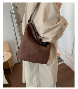 Detail of dark brown suede tote bag featuring premium stitching and adjustable strap