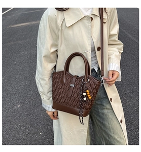 Detail of dark brown woven tote bag with smooth leather handles and colorful beaded tassel