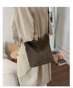 Detail of minimalist dark brown suede tote bag featuring vertical stitching and a slim strap