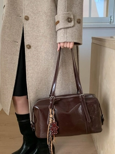 Vintage dark brown oil-wax leather Boston bag held by model in a stylish winter coat