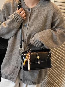 Chic black glossy leather shoulder bag with golden buckle and colorful beaded charm