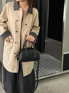 Grande borsa Boston in pelle nera con cuciture bianche e trench kaki di tendenza