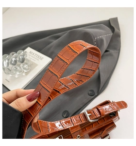 Detail view of brown crocodile embossed leather strap with polished silver buckle