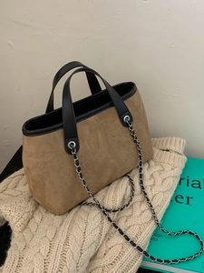 Minimalist brown suede tote bag for women with black leather handles on a cozy sweater