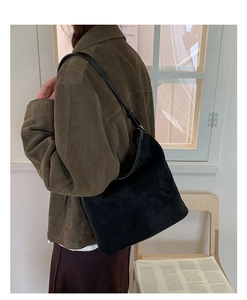 Detail view of a large black suede tote bag showing soft drape and leather strap