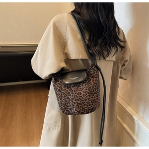 Close-up of leopard print crossbody bag featuring a black leather flap and slim strap