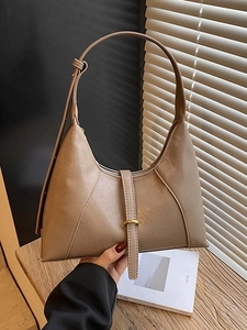Chic beige soft leather half-moon baguette bag with elegant gold ring and shoulder strap