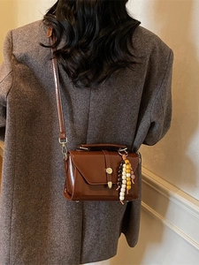 Brown vintage patent leather flap handbag with beaded tassel detail on a fashion model