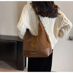 Detail of brown faux suede hobo tote with leather trim and silver metal brand lettering