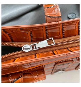 Macro shot of brown crocodile texture leather and silver metal zipper on a retro handbag