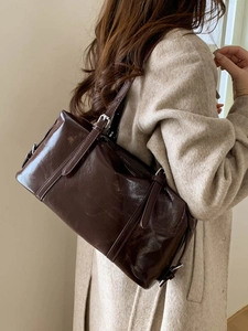 Retro deep brown oil wax leather Boston bag worn by a model on a beige wool coat