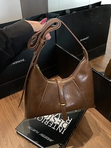 Retro dark brown crescent shoulder bag in oil wax leather finish with a minimalist aesthetic