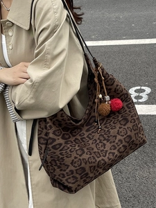 Retro leopard print tote bag with colorful pompom tassels shown in a street style shot