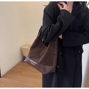 Detail showing the brown suede and leather patchwork with metallic logo on a hobo bag