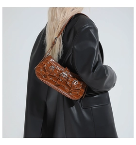 Detail of dark brown crocodile texture leather bag with silver rivets and punk buckles