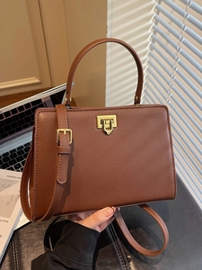 Minimalist dark brown leather commuter handbag with gold square clasp and shoulder strap