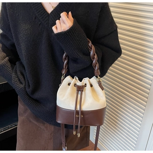 Detail of cream and brown bucket bag with braided handle and gold AERYD logo