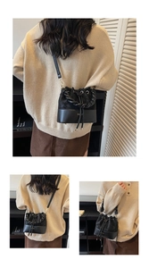 Detail view of black drawstring bucket bag with gold logo and woven handle texture