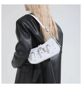 Detail of white crocodile texture underarm bag with silver buckles and punk style rivets