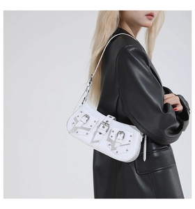 Detail of white textured shoulder bag featuring silver buckles and rivet pocket accents