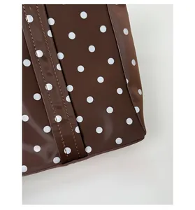 Detail of glossy brown polka dot fabric with precise stitching and waterproof coating