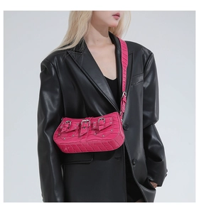 Detail of fuchsia crocodile texture underarm bag with silver buckles and studs