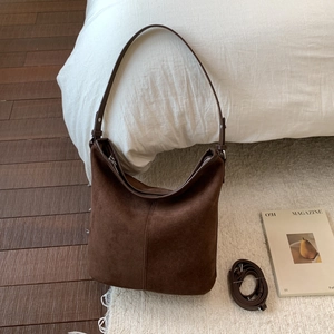 Macro view of brown suede tote bag featuring detailed stitching and dual strap design