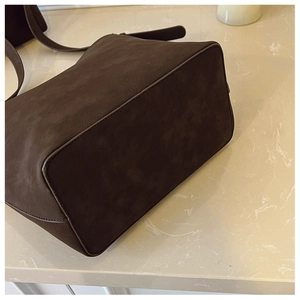 Detailed view of the dark brown matte suede texture and precise stitching on the tote bag