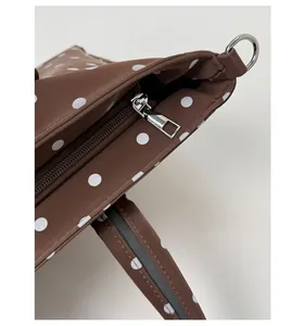 Detailed macro shot of the silver-tone metal zipper and D-ring on the polka dot tote bag