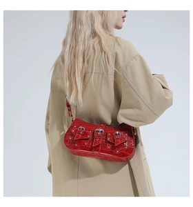 Detail of red crocodile pattern shoulder bag with silver rivet buckles on a trench coat