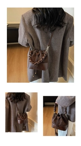 Detail of dark brown leather bucket bag with woven handle and drawstring closure