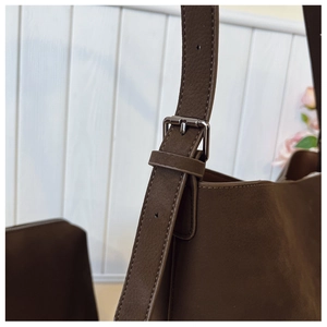 Detail of adjustable shoulder strap and silver metal buckle on brown faux leather bag