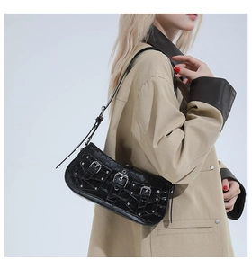Close-up of black crocodile pattern shoulder bag with silver buckles and metal rivets