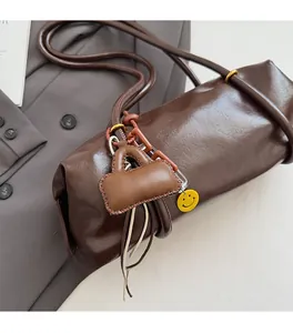 Detail of dark brown leather Boston bag with trendy mini charm and yellow smiley pendant