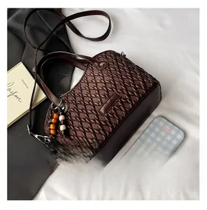 Macro shot of dark brown woven bucket bag with beaded charm and slim shoulder strap