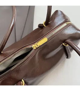 Close-up of smooth gold zipper on dark brown leather shoulder bag with sleek fabric lining