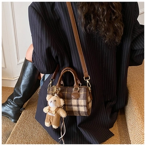 Detail of checkered Boston bag with brown leather strap and mini plush bear charm