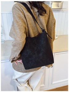 Detailed view of matte black suede bucket bag showing texture and shoulder strap fit