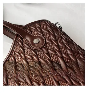 Close-up of dark brown woven texture on a tote bag with silver metal rivet detail