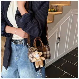 Detail of checkered plaid Boston bag with teddy bear charm and brown leather straps