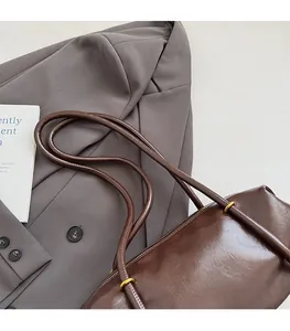 Detailed close-up of dark brown leather texture with golden metal hardware on tote bag