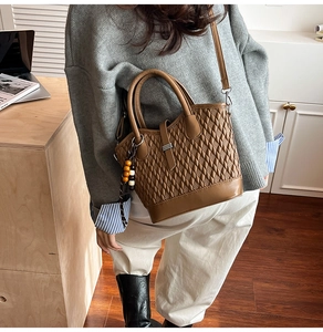 Brown quilted crossbody bag with beaded pendant shown in a stylish lifestyle scene