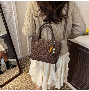 Detail of dark brown pleated woven bucket bag with beads and detachable strap
