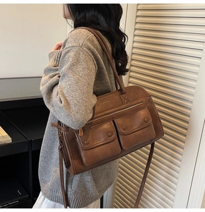 Detailed view of brown retro leather bag with double front pockets and metal hardware